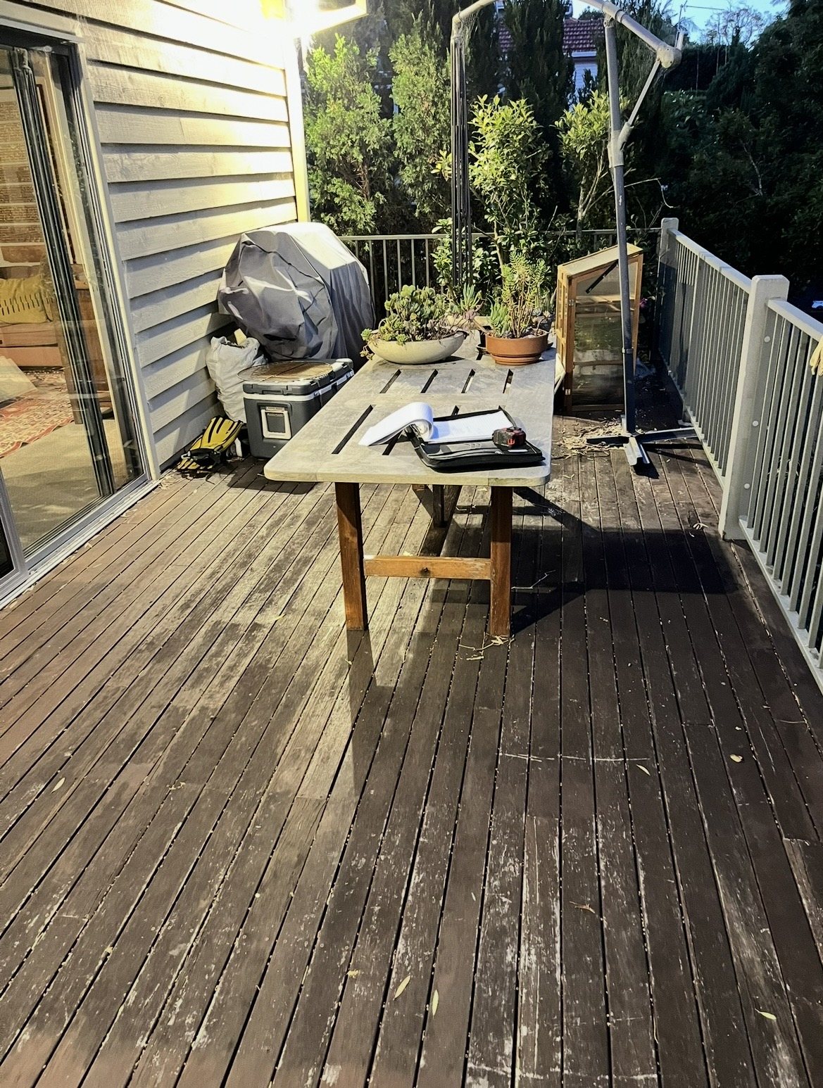 Before: worn, patchy timber deck cluttered with furniture and gear