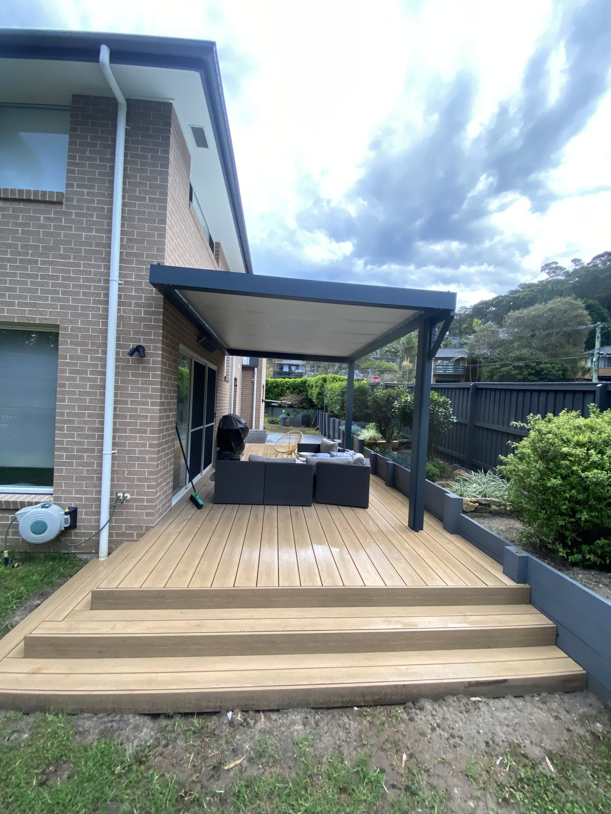 Timber deck with dark pergola cover and outdoor lounge