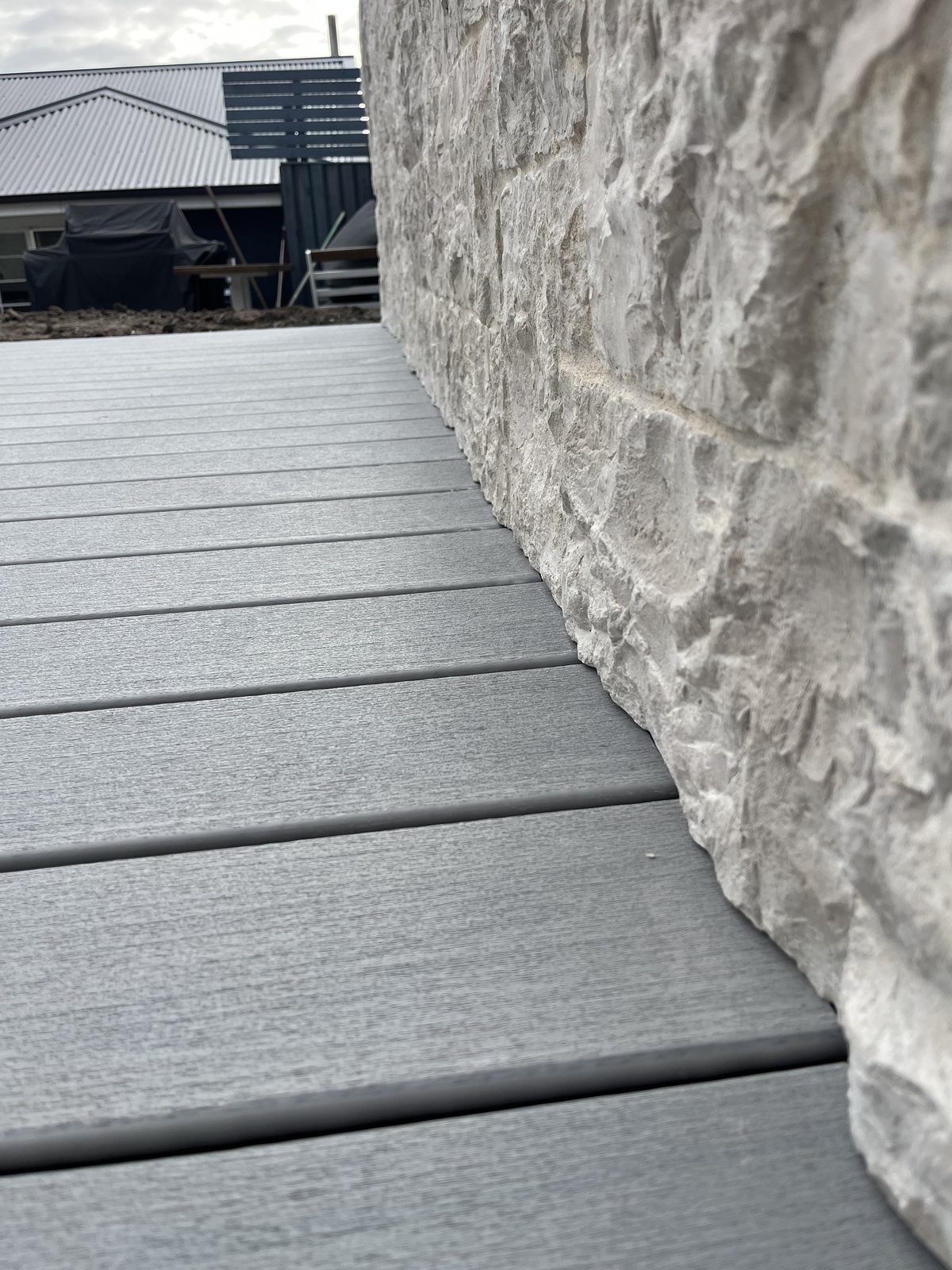 Composite deck board edge detail against sandstone