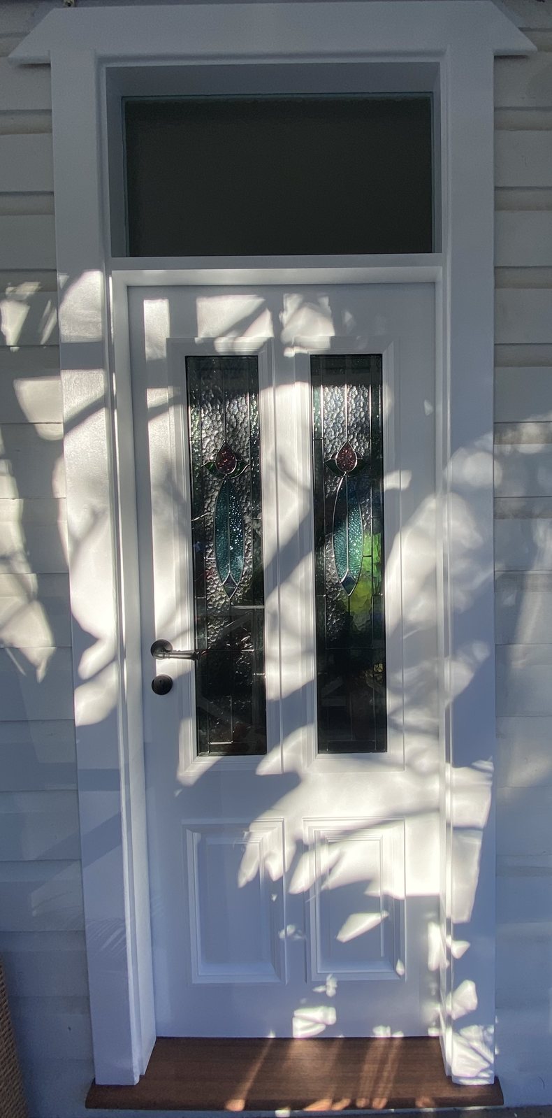 White door with coloured stained glass panels, sunlit