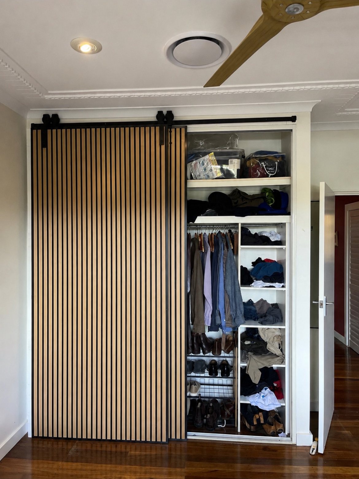 Slat sliding wardrobe door revealing a walk-in closet