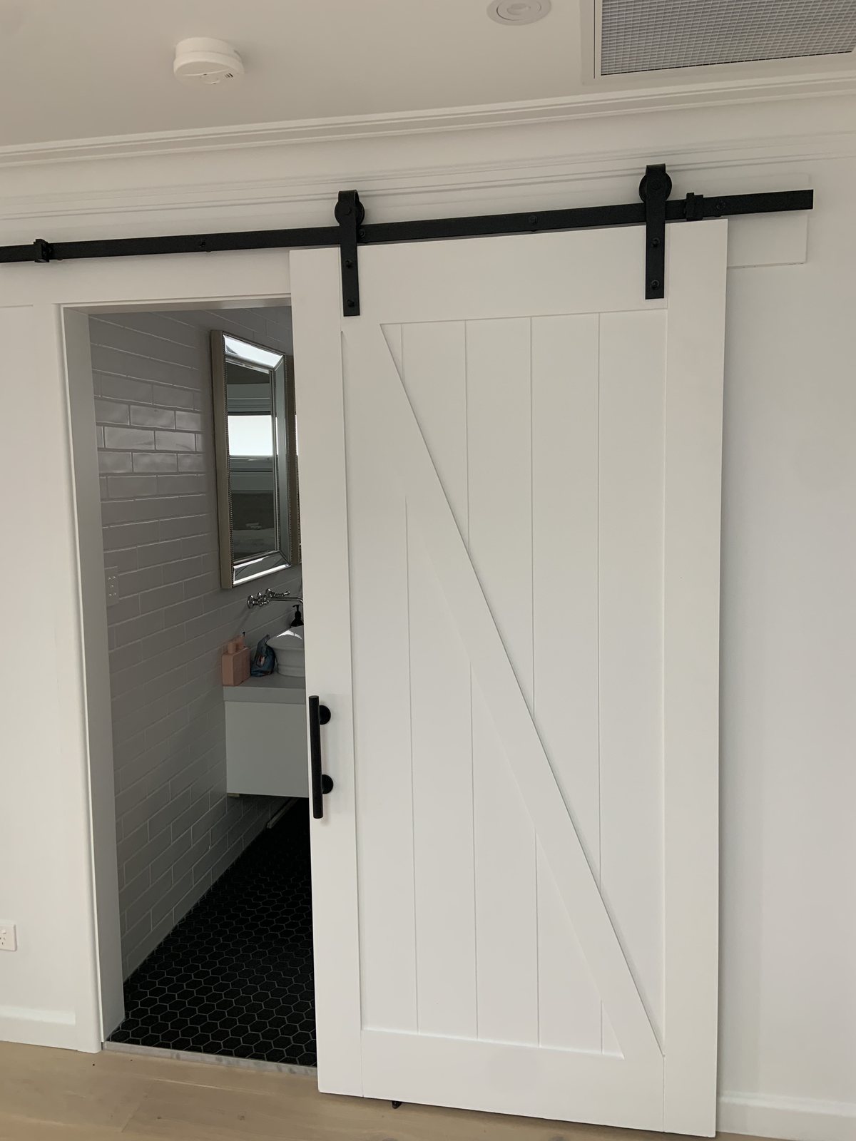White Z-brace sliding barn door into a bathroom