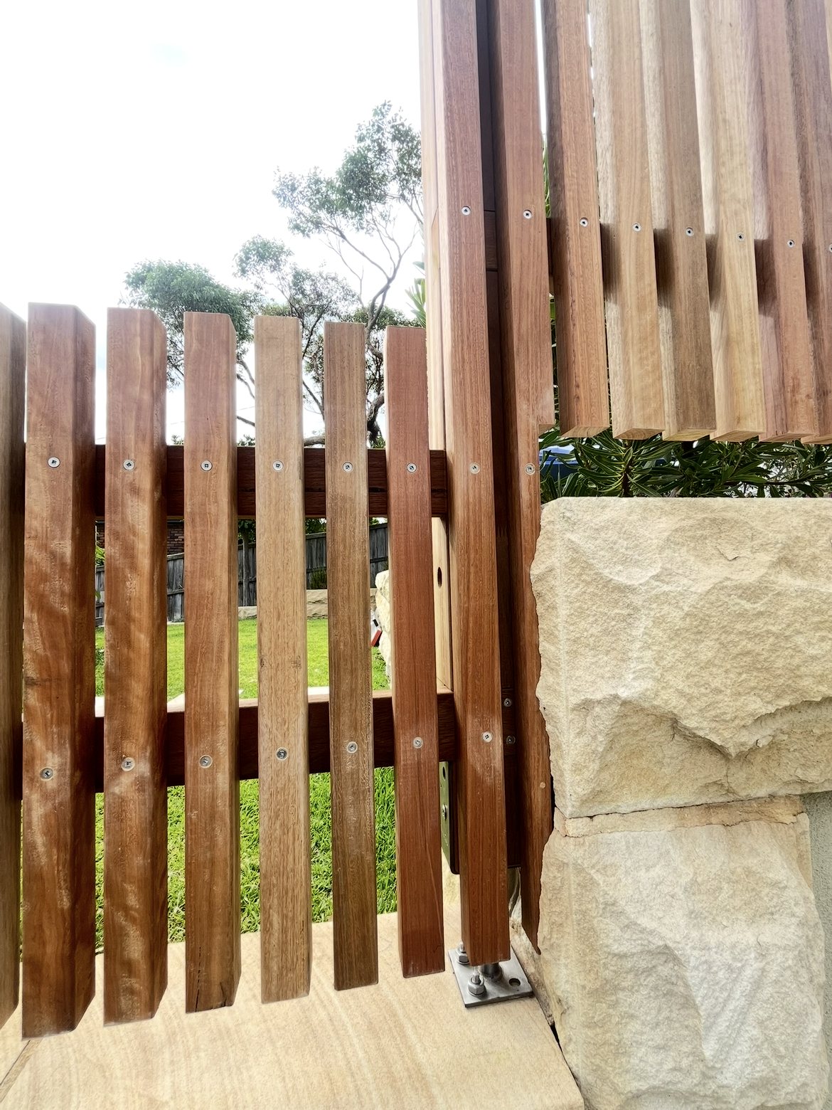 Slat gate hinge and post detail against sandstone