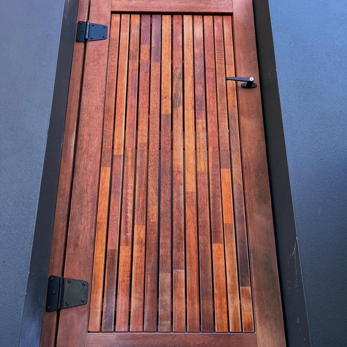 Close-up of vertical slat gate hinge detail on sandstone