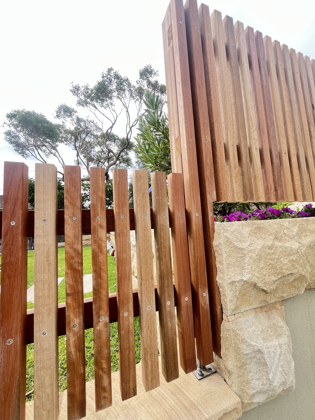 Vertical slat gate detail beside a sandstone planter