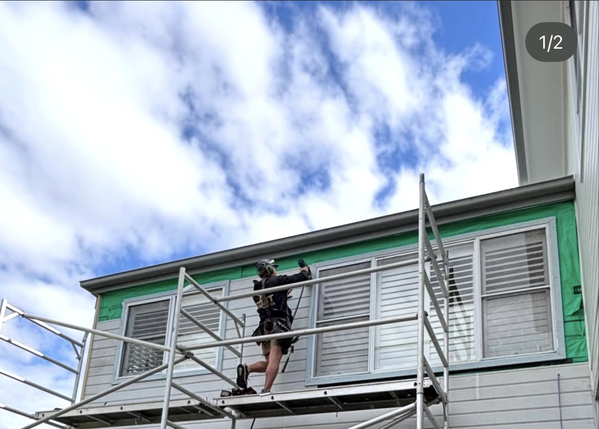 Carpenter on scaffold installing exterior cladding