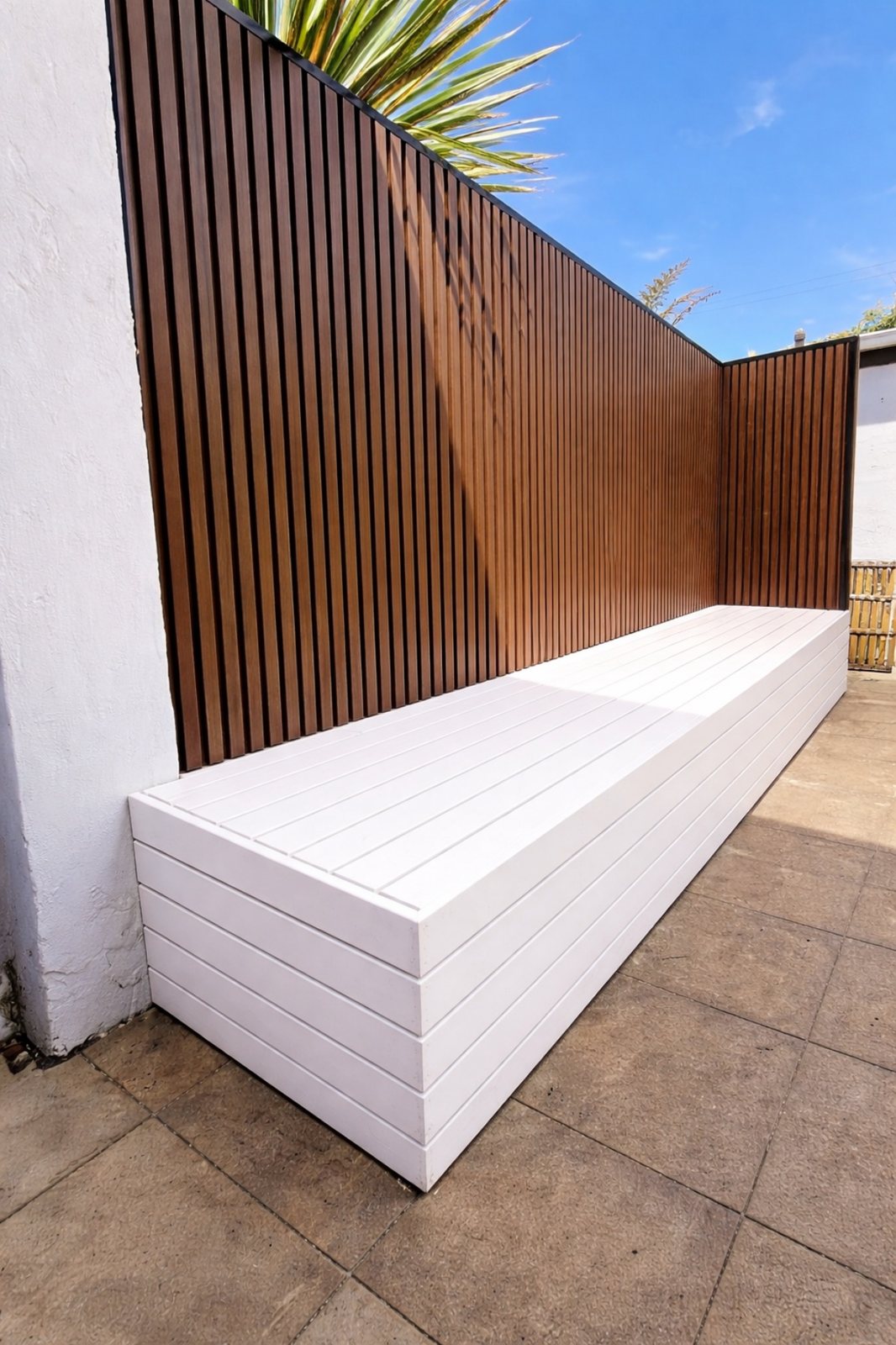 White built-in storage bench below a slat privacy screen